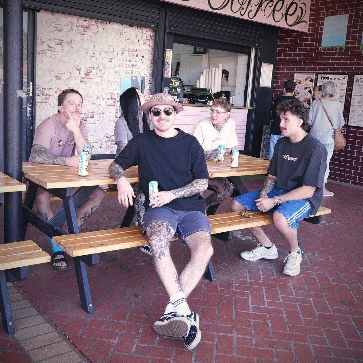 Friends sitting with Stay Wicked cans at the picnic tables outside Love Street Coffee, Cloverdale